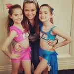 Dance mom and daughter at a dance convention, smiling and posing for a photo