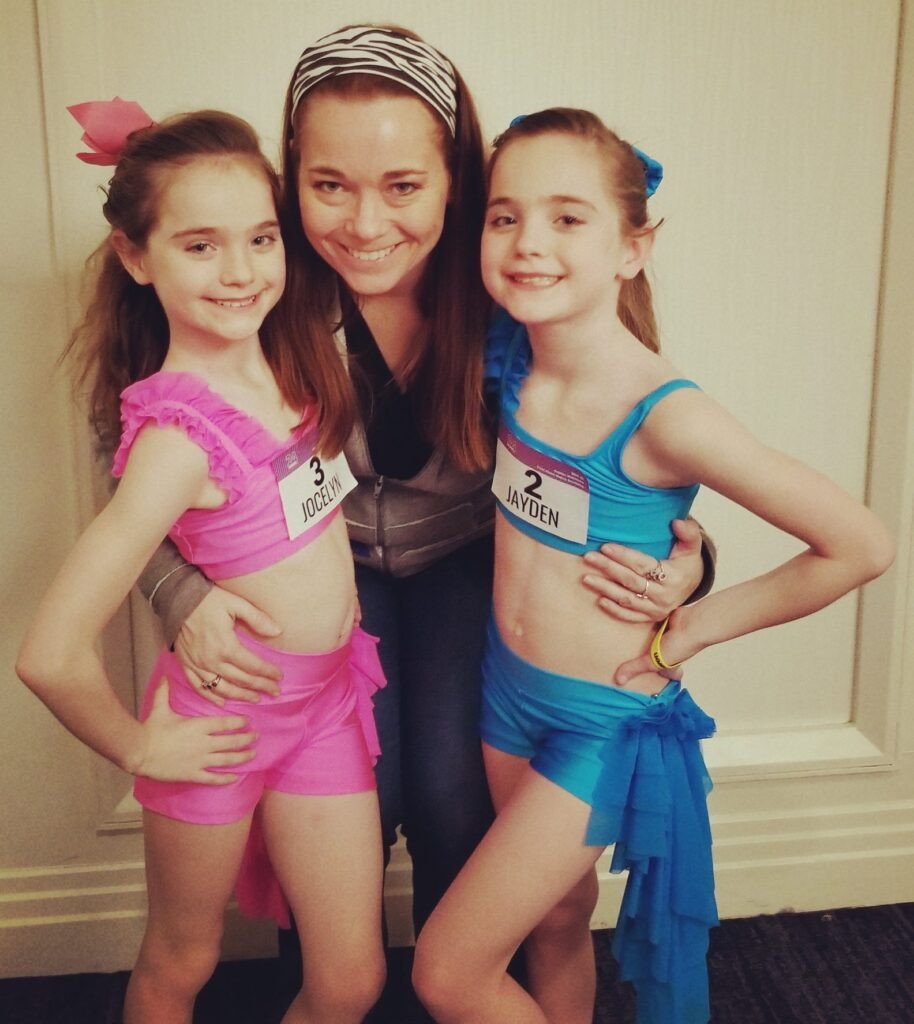 Dance mom and daughter at a dance convention, smiling and posing for a photo