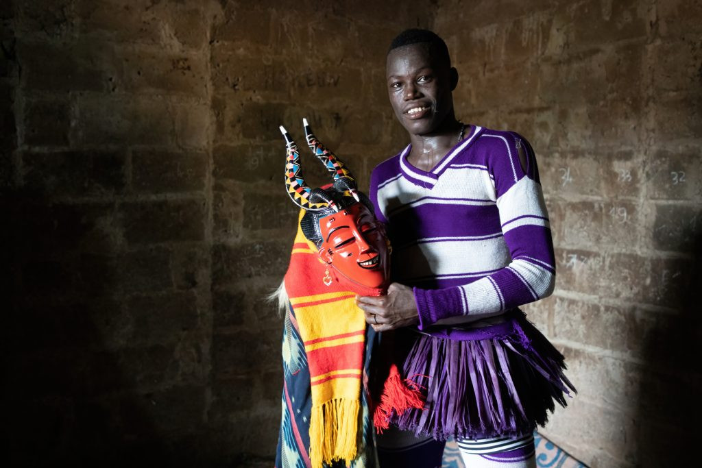 Unveiling the Man Behind the Zaouli Mask: A truly special encounter with a Zaouli dancer without his mask, holding the Djela, providing a unique insight into this celebrated Ivorian tradition.