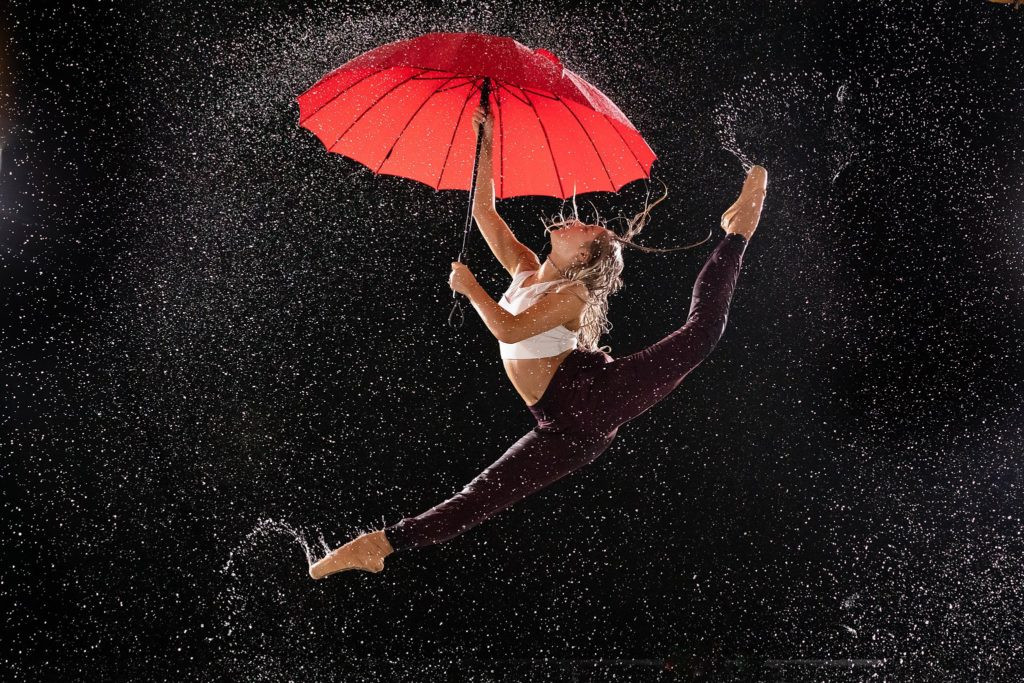 Creative rain dance photography session with a dancer splashing in puddles.