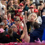 A man raises his fist as he taken away on a stretcher