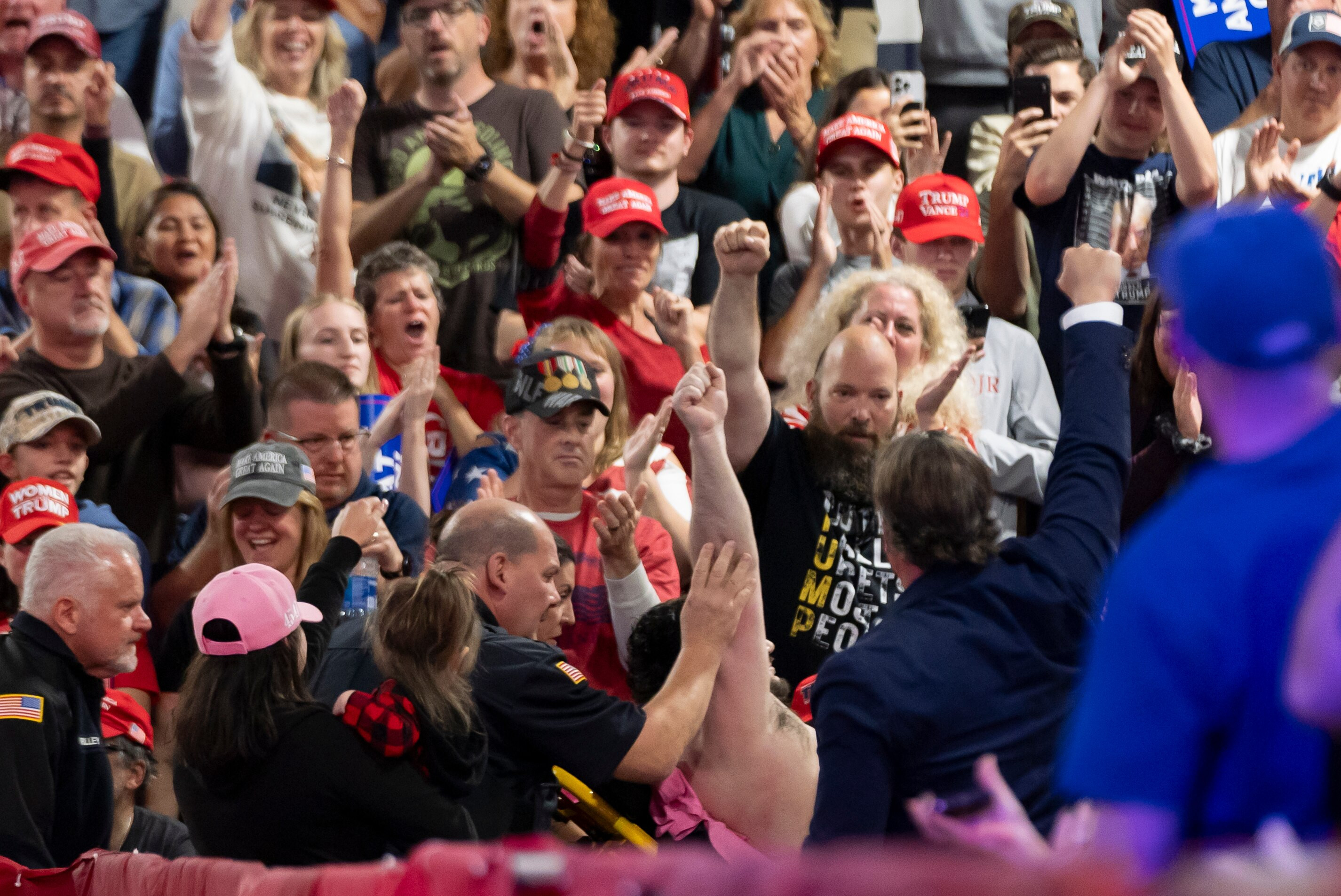A man raises his fist as he taken away on a stretcher