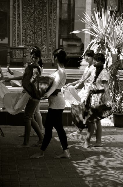 A close-up shot captures the delicate hand movements of a young dancer, crucial in the expressive art of Balinese dance.