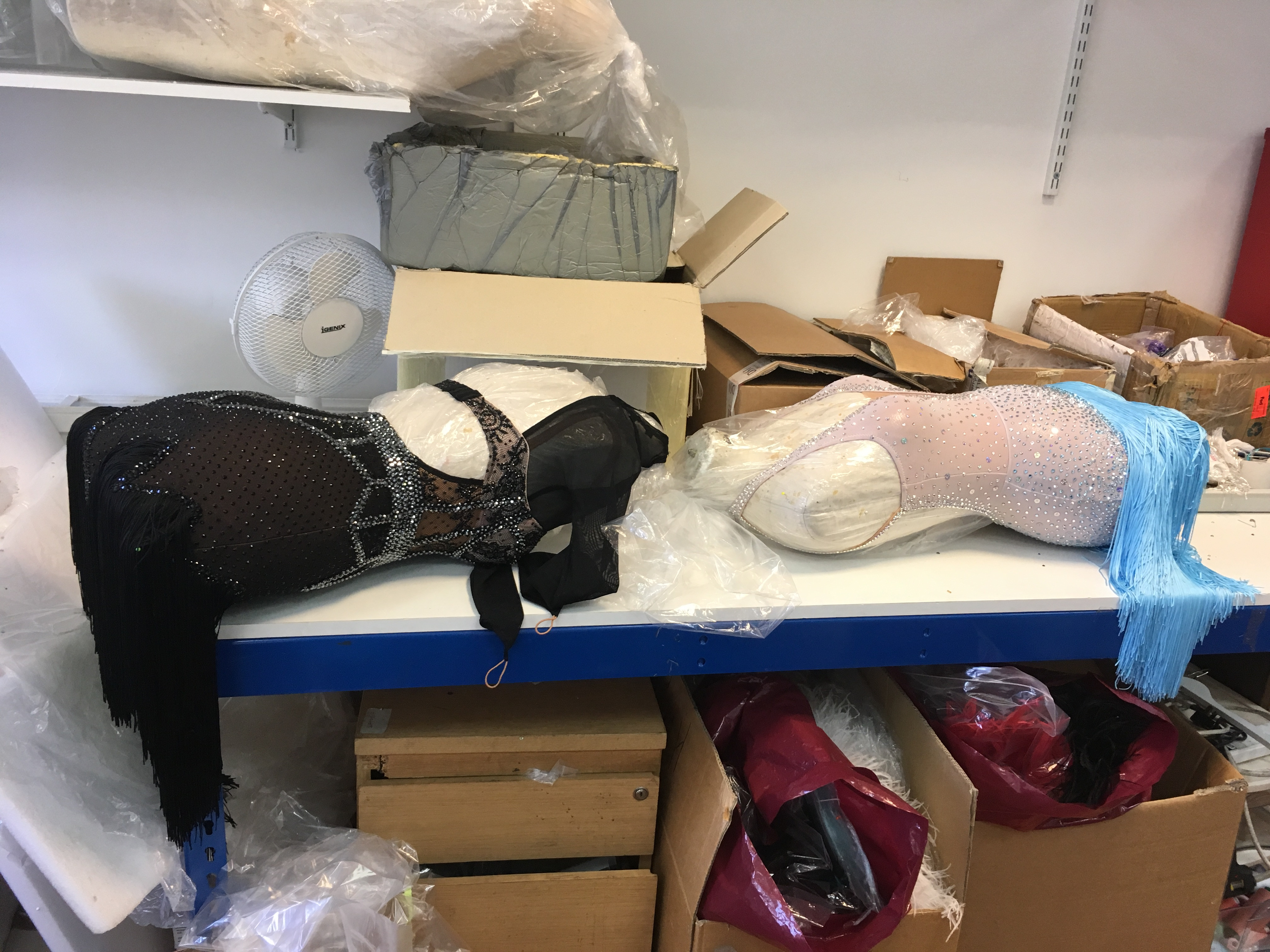 Mannequins adorned with beaded dance costume elements, illustrating the scale and ongoing nature of the embellishment process within the workroom.