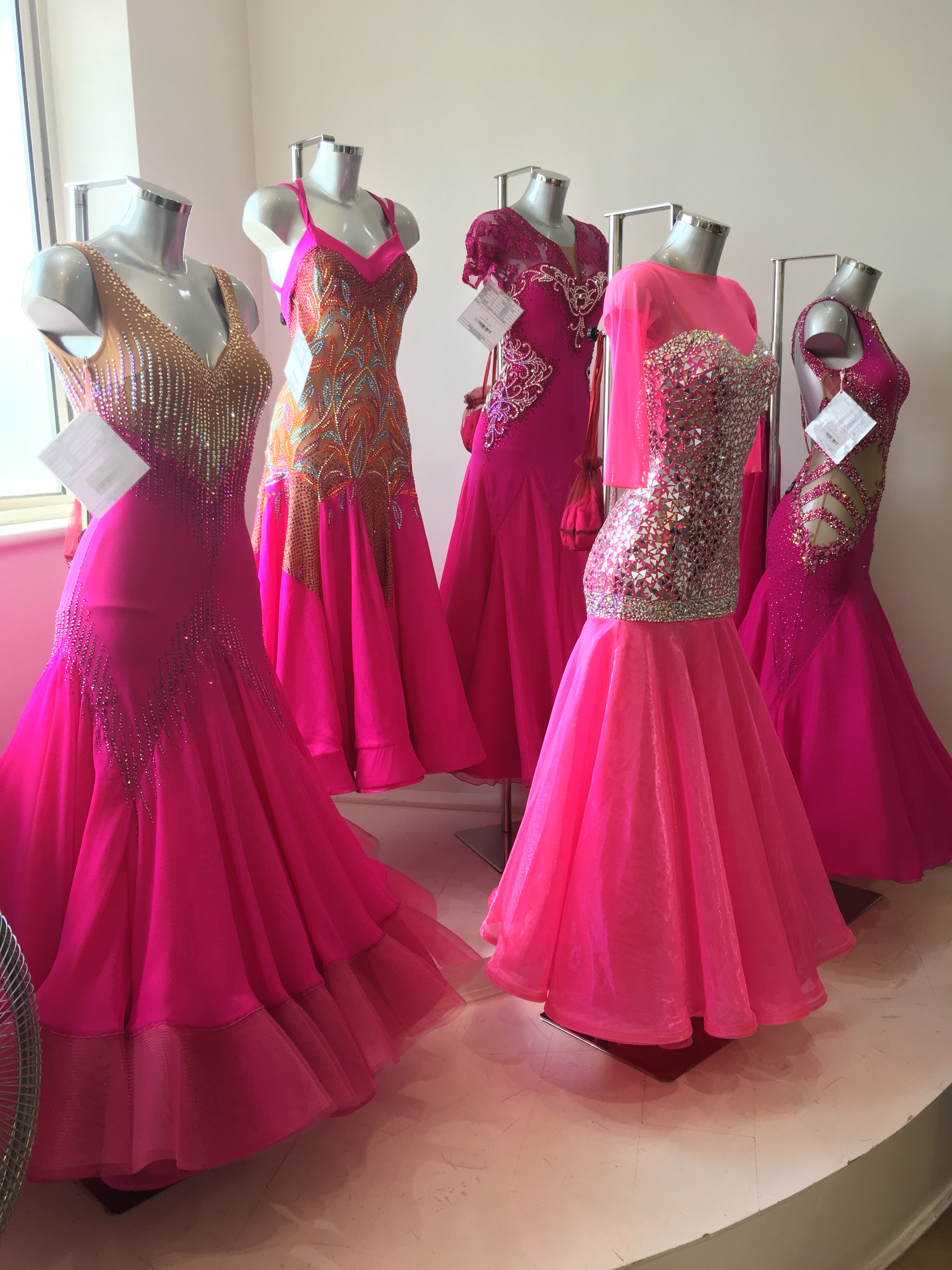 Close-up on a selection of made-to-measure dance dresses, emphasizing the luxurious fabrics and detailed designs of couture dancewear.