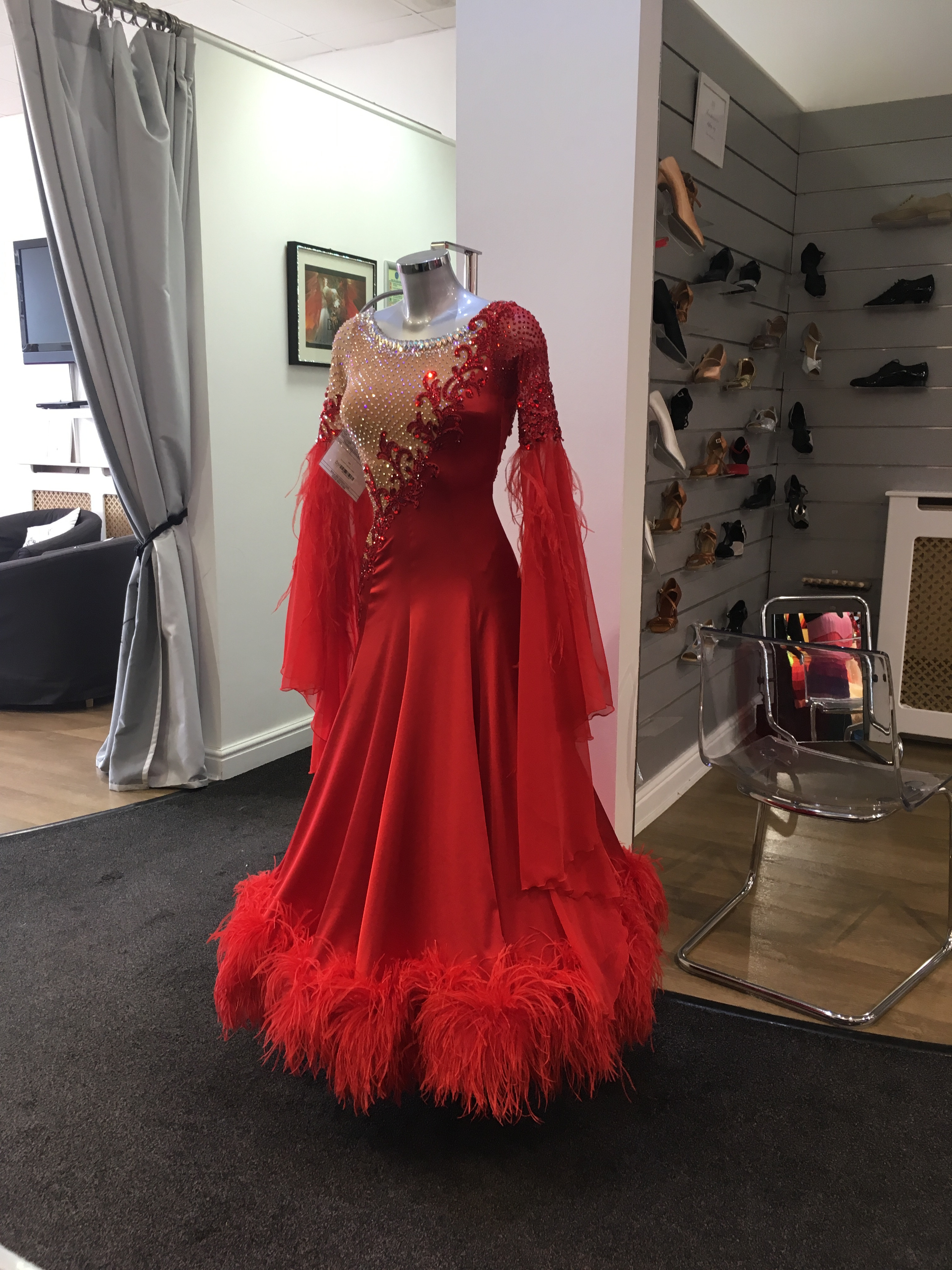 A rack of vibrant, custom-made couture dresses, displaying the variety and high-end craftsmanship of ballroom dance costumes.