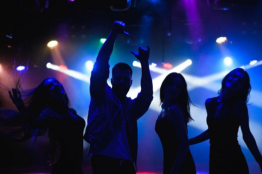Man dancing in a club with confidence and rhythm, showcasing basic steps like the two-step, bounce, side-to-side rock, and triangle step, embodying the essence of rhythm and confidence in club dancing.