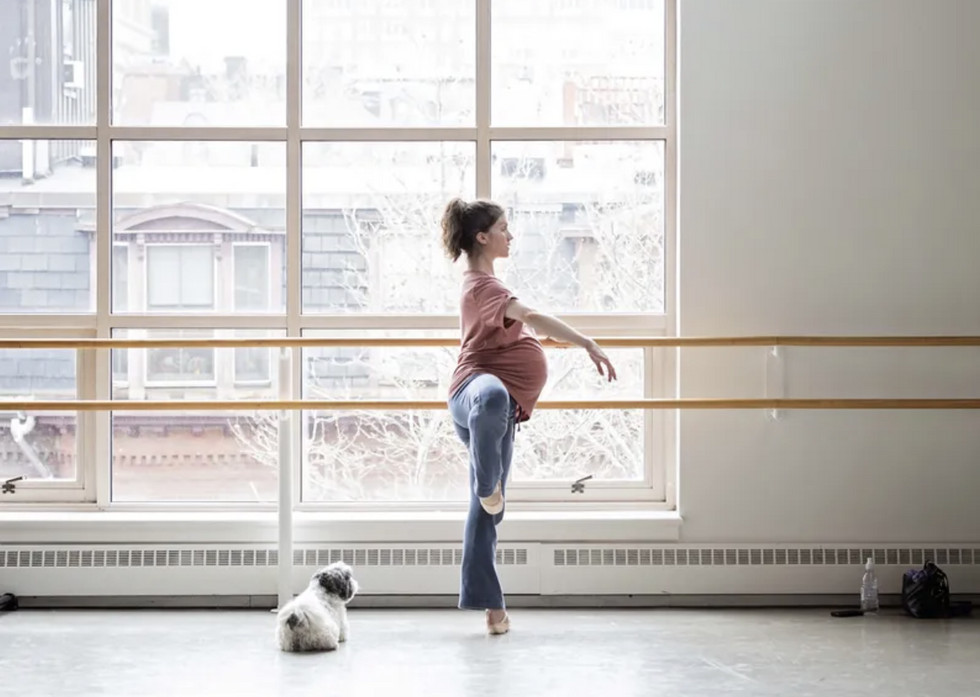 A pregnant dancer in a supportive pose, showcasing the strength and grace of dancing during pregnancy.