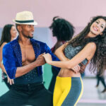 Two salsa dancers smiling and posing during a dance class