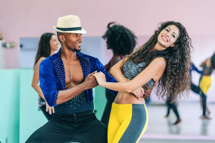 Two salsa dancers smiling and posing during a dance class